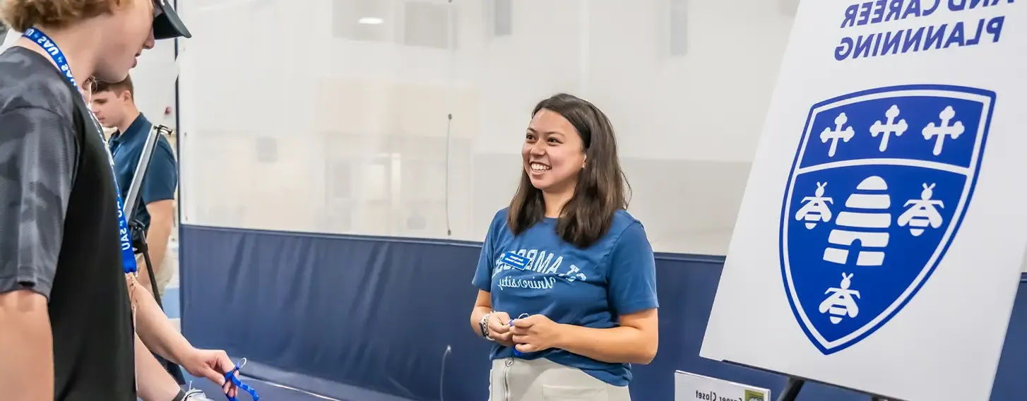 A student standing at a table with a woman at the Career Center.