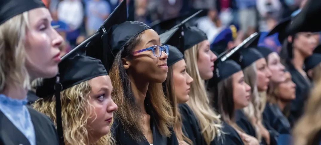 Graduates in a row looking upward during commencement ceremony.